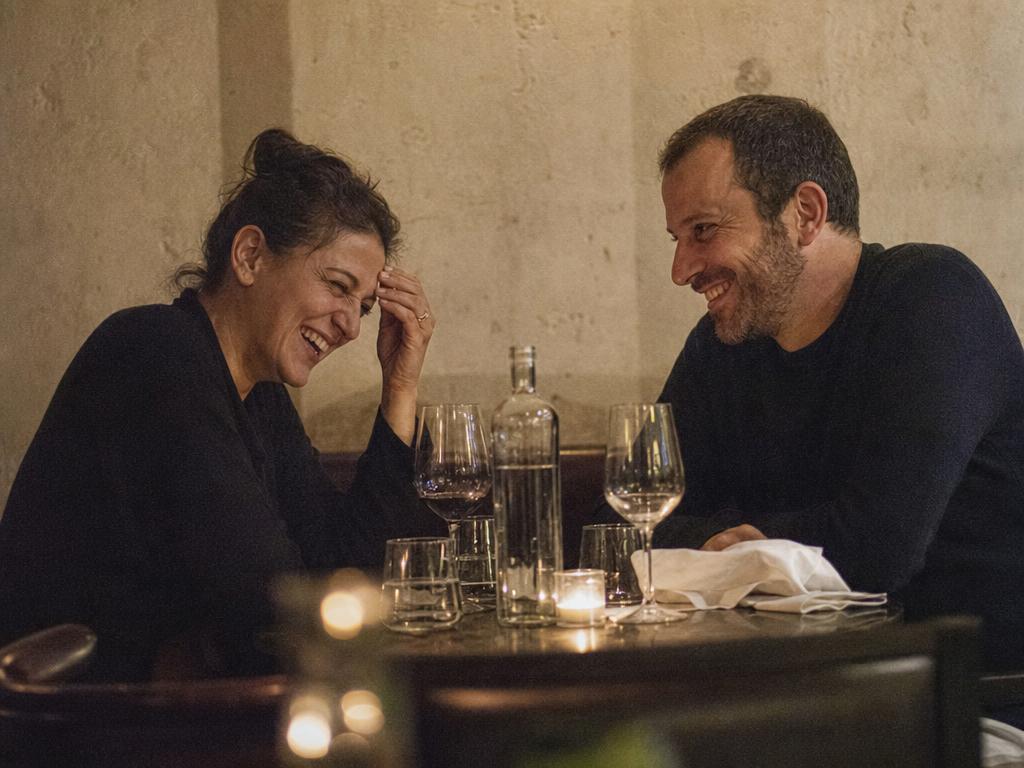 Two men laughing together over drinks in a warmly lit restaurant
